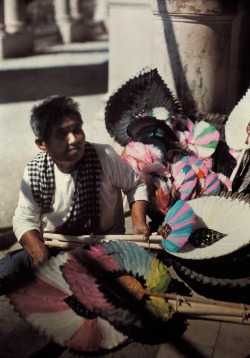 natgeofound:  A woman sits selling feather fans as souvenirs