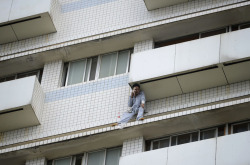appil:  A patient sits outside a hospital building in Changsha, Hunan province, China, on June 25, 2014. Firefighters saved the patient who broke a window on the eighth floor and attempted suicide. The patient was sent to the hospital after a car accident