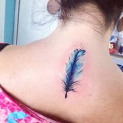 tattoofilter:  Blue watercolor style feather tattoo on the upper back. Tattoo artist: Adrian Bascur