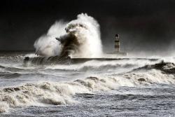 awkwardsituationist:  waves in excess of one hundred feet dwarf the seaham lighthouse in county durham, england. photos by owen humphries 