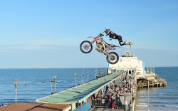 twenty20four4:  Bournemouth, Dorset, England, United Kingdom: A crowd of onlookers watch as a motorcycle stunt rider flies over a pier during the Wheels Festival in Bournemouth. Campbell Rowley/EPA