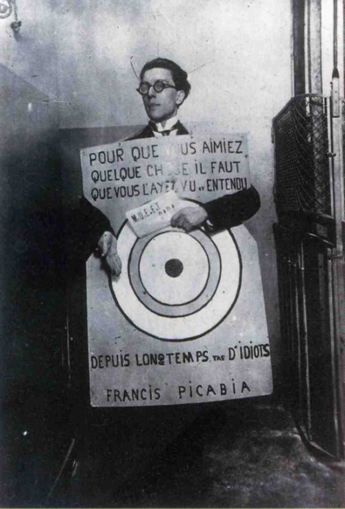 André Breton at a Dada festival in Paris on March 27th, 1920, wearing a sandwich board with text from Francis Picabia that reads: "In order to love something you have to have seen or heard it for a long time you bunch of idiots.“