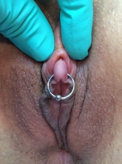 pussymodsgaloreA very nice clit, pierced and with a ring through it, the clit hood being retracted (by the gloved fingers of the piercer?).  Beautiful