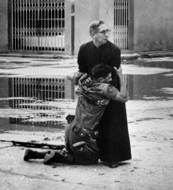 adaltaredei:  Powerful photo of a priest holding a dying soldier while bullets are fired around them. Venezuela, 1962 