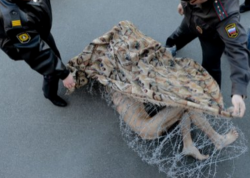 valkania:  Russian art student Peter Pavlesnkiy wrapped himself in barbed wire. The confused policemen attempted to untangle and remove him from the public square — first by putting a blanket to hide the horror, then with wire cutters. The protestor