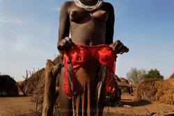 Ethiopia’s Omo Valley, by Olson and FarlowBras come to Omo: On our second trip (late 2009), the writer and I both notice that the first bras had come into these villages.  This woman is holding her new bra out to dry after washing it by squirting water