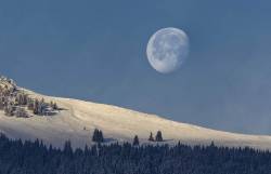 The moon sets as the sun begins to rise over the mountains near Untervaz, Switzerland