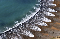 sixpenceee:  Waves create a striking pattern on a sandy beach in Dorset, England