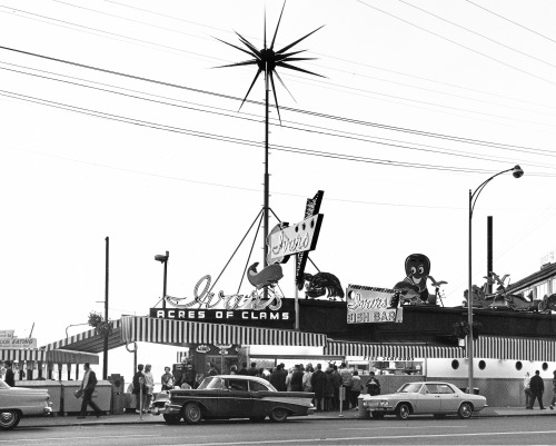 elizabethgraves:  fusiondesignvintage: The original Ivars Acres of Clams with acres of neon signage in the 1940s.  Encore des structures tout en hauteur pour attirer l’attention de loin.   Still tall structures to draw attention from afar.   (Source