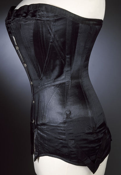 historicalcorsets:  Corset of boned black satin with metal fastenings, ca. 1900.