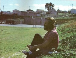 palace-of-exile:  1971- Jim Morrison sitting on hill in Redondo Beach (South Bay) putting Adidas on. Originally from Frank Lisciandro’s ‘A Feast of Friends’.