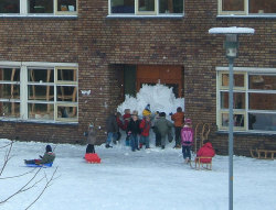 yanadamos:  Unos niños estadounidenses, durante el recreo, tapian con nieve la puerta de la escuela para evitar tener que entrar de nuevo.
