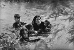 historicaltimes:  A mother and her children wade through a river in Loc Thuong during the Vietnam War to escape US bombing - Kyōichi Sawada via reddit 