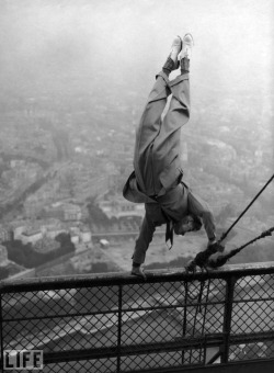 A dapper daredevil balances on a handrail at the top of the Eiffel Tower in Paris, 1935.