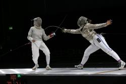 Modernfencing:  [Id: Two Sabre Fencers In A Bout. The Fencer On The Right Is Lunging
