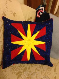 shinykari:  Finished my Kree star pillow! I am, *ahem* rusty at certain parts of quilting and/or finishing, and also apparently can’t measure. Ah well. The small star in the middle is actually in gold thread; the purple is disappearing ink that hasn’t