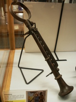 Shame Flute. The round part goes around the neck and the finger are smashed beneath the iron bar to give the illusion that the musician is playing his instrument.