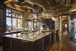 homestratosphere:  This gorgeous kitchen features soaring exposed beams and large stone brick walls. A massive island stands next to a wooden dining table. Source: https://www.zillow.com/digs/Home-Stratosphere-boards/Luxury-Kitchens/