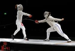 Modernfencing:  [Id: Two Sabre Fencers In A Bout. The Fencer On The Left Is Parrying