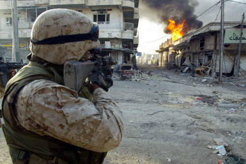 konflict23:    A US marine from the 3/5 Lima company points his rifle at a building as it burns in the restive city of Fallujah,14 November 2004.     My sister company 
