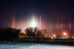 nubbsgalore:  atmospheric light pillars are created by the reflection of light - whether from the moon, setting sun or, as here, suburban city light - off millions of flat hexagonal plate shaped ice crystals that have become horizontally aligned as they
