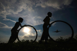 Smithsonianmag:  Photo Of The Day: Children Play With Tires Under A Runway Photo