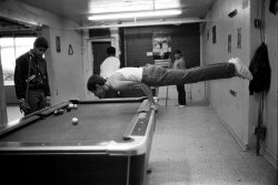 k-a-t-i-e-:  Martin, a teenager, shows off his muscles by doing a pushup on the pool table, 1980s Stephen Shames