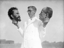 Bernard Tussaud, grandson of Swiss modeller Madame Tussaud, holds two wax heads, one of Haile Selassie, Emperor of Abyssinia (Ethiopia) and the other of Italian dictator Benito Mussolini. September 1935.