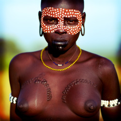 nativenudity:  A Mursi girl, decorated with body paint and scarification.