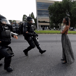 arrest-my-skin:  thingstolovefor:    “A woman was standing calmly, her long dress the only thing moving in the breeze, as two police officers in full riot gear confronted her in the middle of a roadway to arrest her. She had no facial expression at