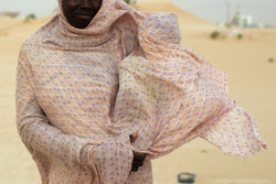 fotojournalismus:  A woman shields her child from the wind while walking on sand dunes in Nouakchott, Mauritania on June 22, 2014. (Joe Penney/Reuters) 
