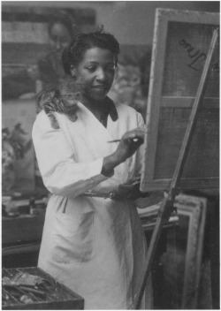 xoviki:Loïs Mailou Jones painting in her Paris studio in 1937 or 1938, with kitten supervising from her shoulder