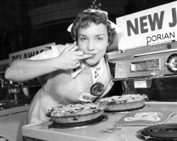 grapnel:  A cheeky Jersey girl playfully flips the bird while sampling some cherry pie.  Apparently taken at a national cherry pie contest - ca. 1957(?). 