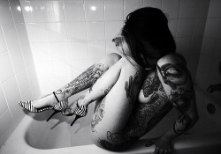Tättowierte Schönheit in Schwarzweiß auf dem Badewannenrand. Großartiges Foto, was wie kaum ein anderes Foto die Tattoos der jungen Schönheit in den Vordergrund stellt, ohne allein auf diese zu verweisen.