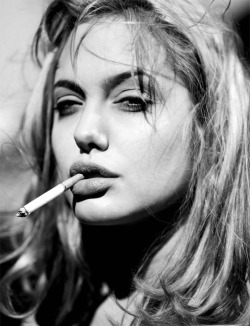Angelina Jolie mit blonden Haaren und Zigarette im Mund.