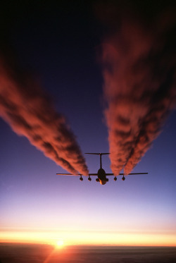 A C-141B Starlifter aircraft leaves four contrails behind it