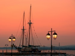 jtkfr:  Sunset on Dapia with traditional vessel and lamp posts. Spetses island, Saronic Gulf, Greece. Photo by Marite2007 on Flickr.com  Smaragdia kie rubinia na su fero
