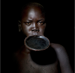 fortheloveofmods:  Surma woman with lip plate - Ethiopia   A Surma / Suri girl will be beautiful if she has a big lip plate, and if her body, is covered of scarifications. They do it with accacia spine and razor blades. Razor blades are the worst thing