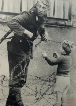 ausschreitungen:  A soldier helping a boy over the barbed wire. After the picture, the soldier was immediately replaced. God only knows what happened to him afterwards. 