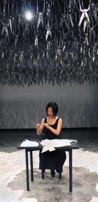 littlewendycat:  alecshao:  Beili Liu - The Mending Project (2011) “…Hundreds of Chinese scissors suspended from the ceiling in a shimmery cloud. The piece involved the artist sitting at a small black table, hand-mending patches of fabric together which
