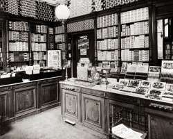 A nice view of the interior of a cigar shop in 1900. All the cigar boxes neatly displayed. Beautiful cabinetry. Note the umbrella holders with drip trays at the floor.