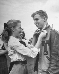 1950sunlimited:  Teen Fads, 1947   Girl ties her hair scarf around her boyfriends neck as a fond token. Boy often gives football sweater as token to his girl.   Why cant life be cute like this still???