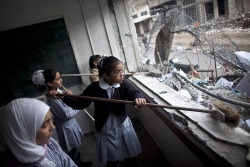 troposphera:  Gaza City, Gaza Strip: Palestinian girls clean debris from their classroom at the al-Shejaia school. The UN-run building sustained heavy damage when Israeli rockets struck a property next door  Photograph: Oliver Weiken/EPA  