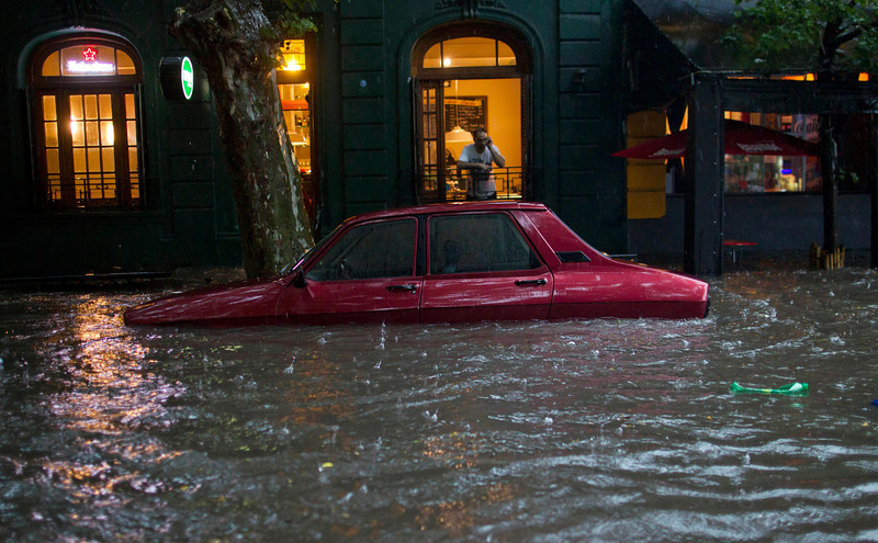 fotojournalismus:  A car is submerged in flood water in front of a home in Buenos